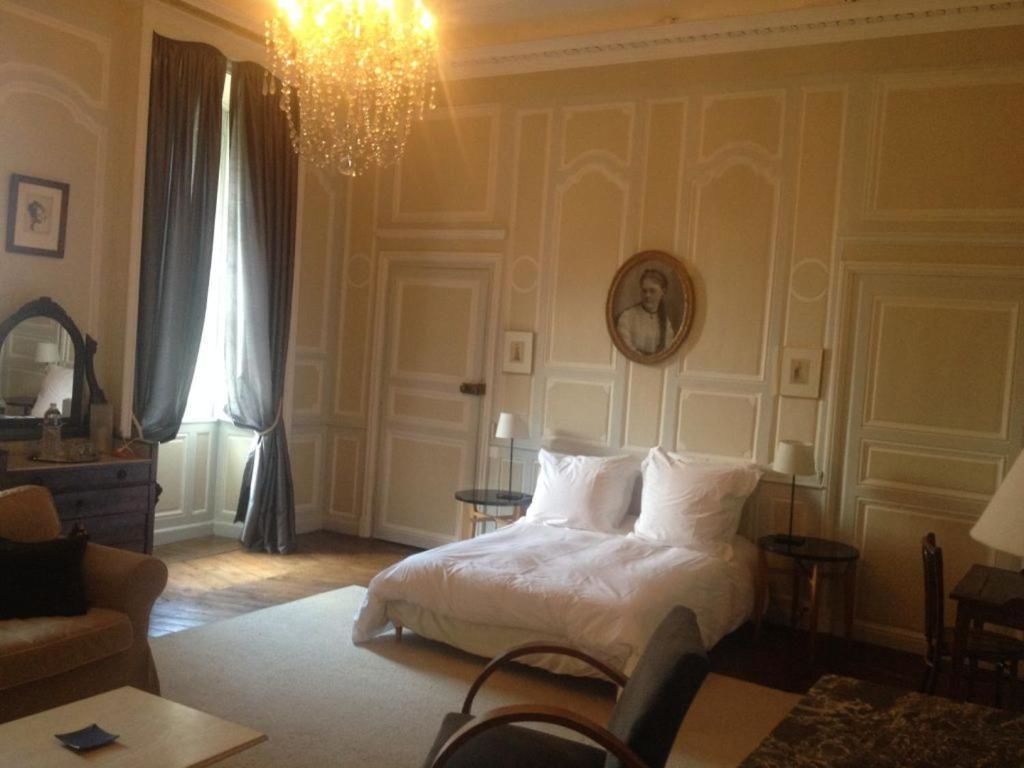 Una habitación de hotel con cama, una silla, una mesa, cómoda, espejo y candelabro.