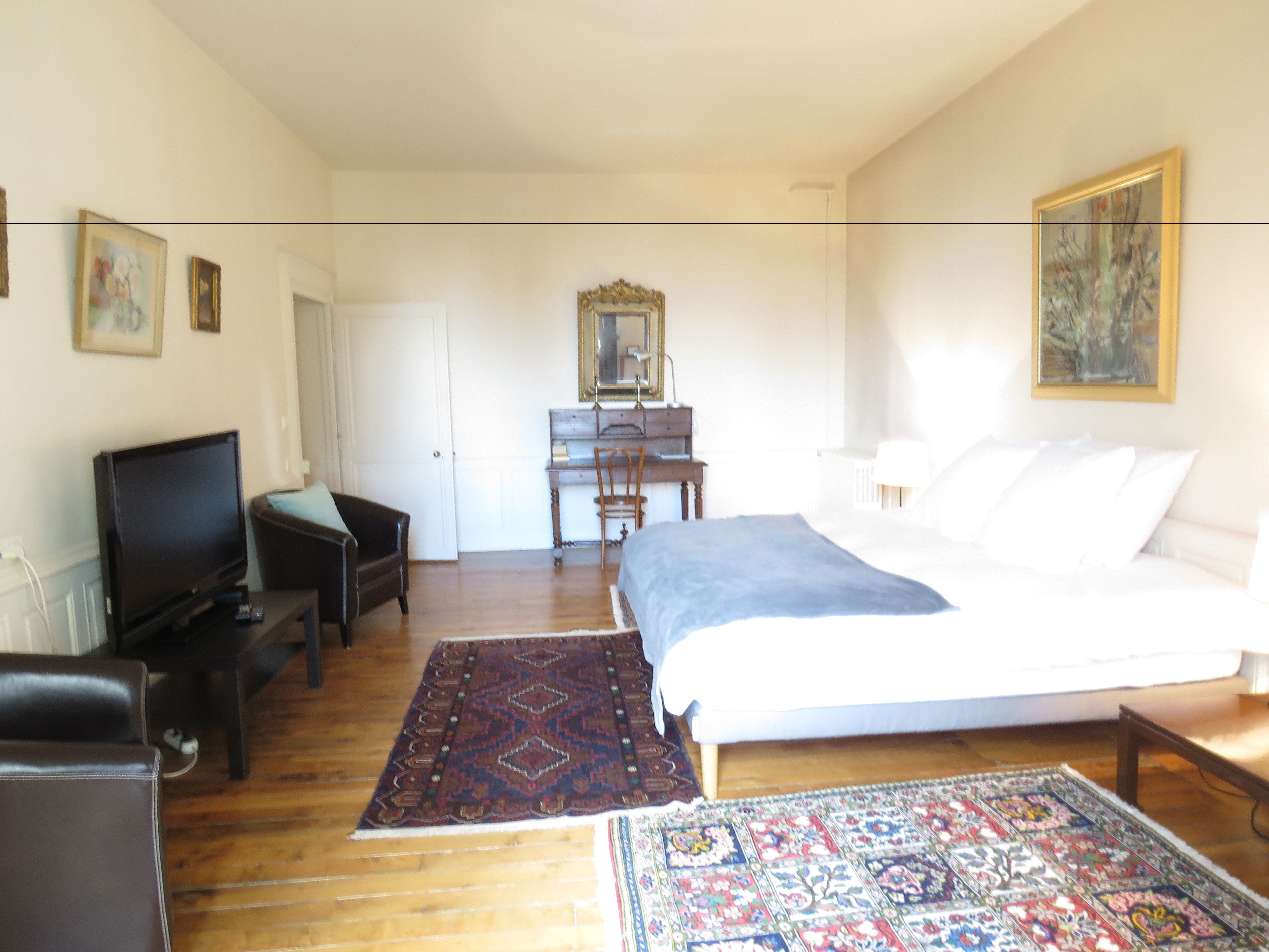 Un dormitorio con cama, escritorio, televisión y silla.
