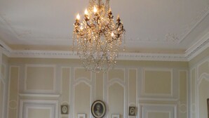 A bedroom with a large bed, two bedside tables, a chandelier, and a chair. - B&B Le Jardin de Carco (Chatillon-sur-Seine)