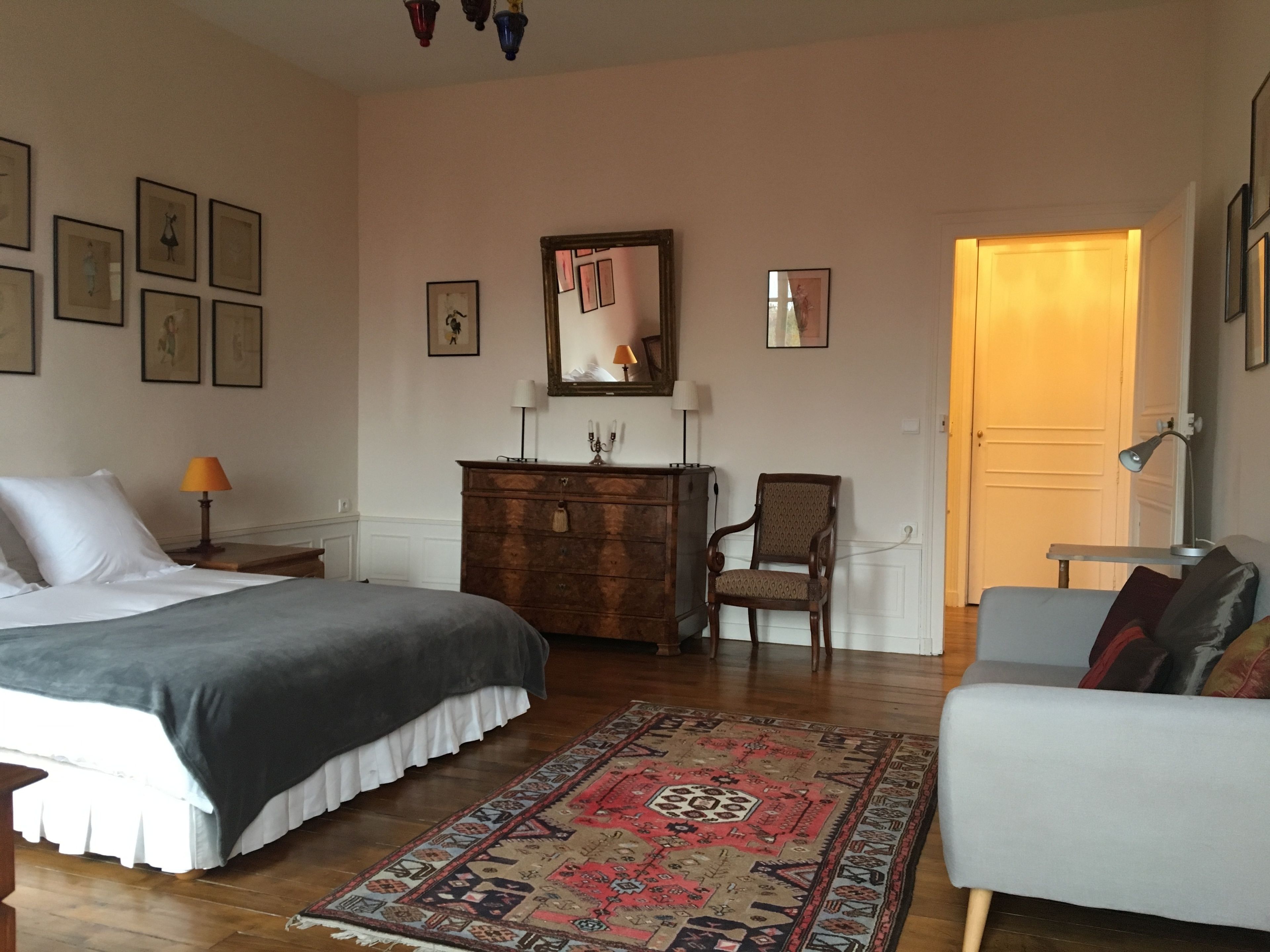 A bedroom with a bed, dresser, chair, and a rug.