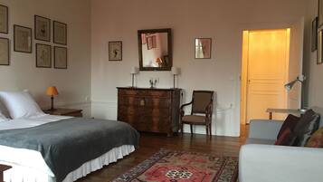 A bedroom with a bed, dresser, chair, and a rug.