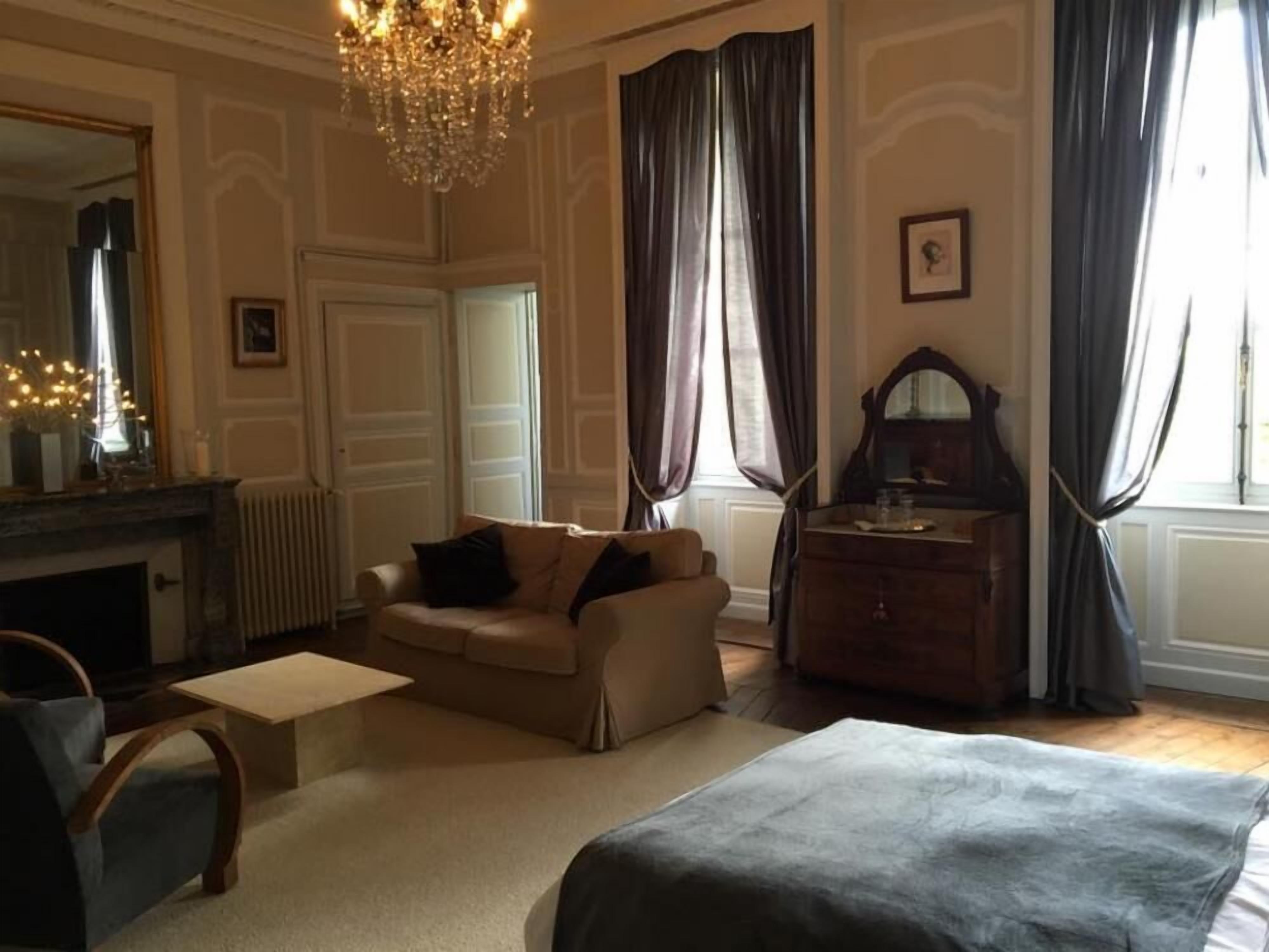Een kamer met een bank, een tafeltje, een kast, een spiegel en een kroonluchter.