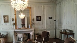 A room with a fireplace, a chandelier, and two armchairs. - B&B Le Jardin de Carco (Chatillon-sur-Seine)