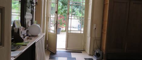 A hallway with a checkered floor, a large rug, and a door leading outside.