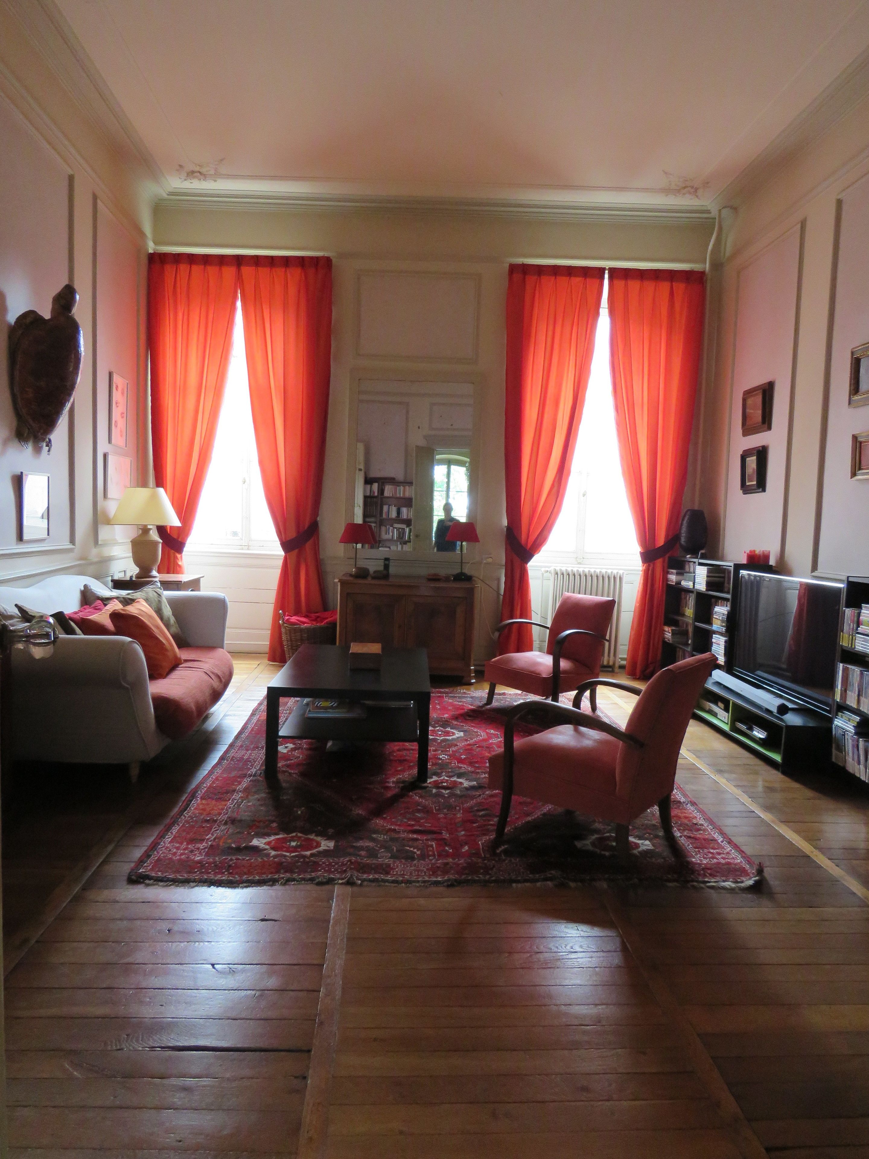A living room with a sofa, armchairs, a coffee table, a television, and a bookshelf.