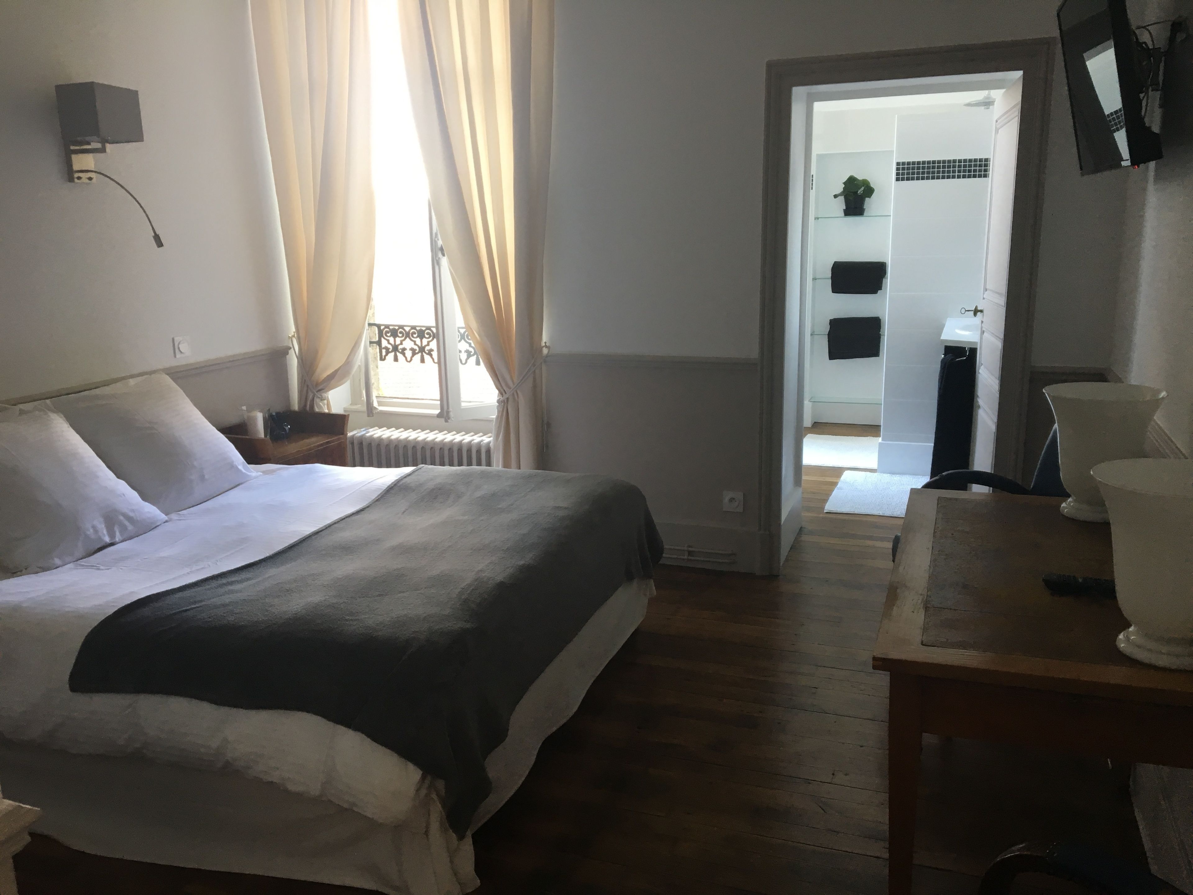 A bedroom with a bed, bedside table, and a view of a bathroom through an open door.