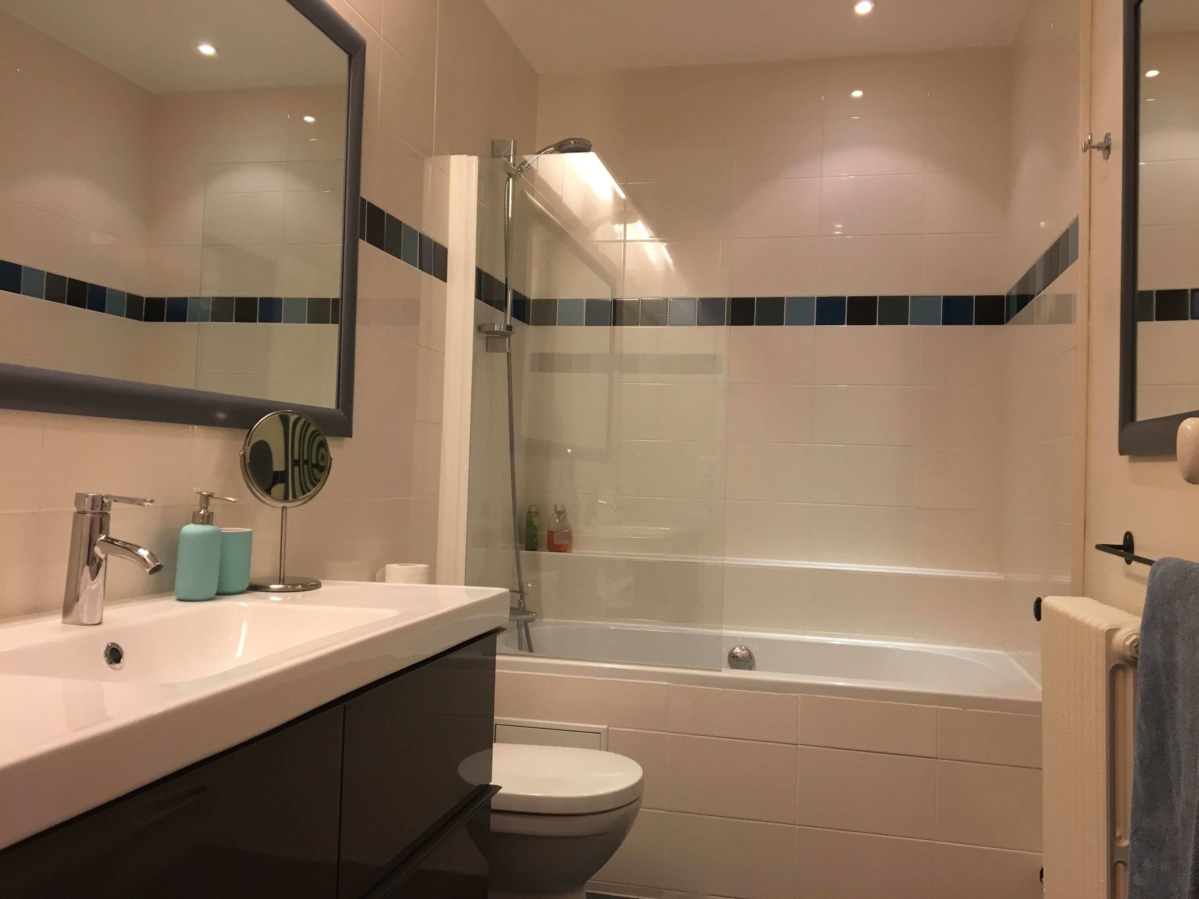 A modern bathroom with a sink, mirror, toilet, and bathtub.