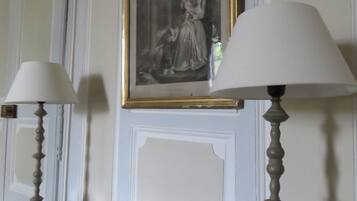A room with a marble countertop, two table lamps, a framed black and white painting, and a small tray with candles.