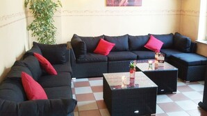 A living room with a sectional sofa, two side tables, and a potted plant. - Gelder Dyck (Kevelaer)