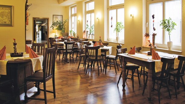 A dining area with wooden tables and chairs, potted plants, and a warm, inviting atmosphere. - Gelder Dyck (Kevelaer)