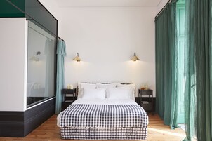 Un dormitorio con una colcha a cuadros, dos mesitas de noche con lámparas, un armario y cortinas verdes.