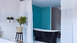 A two-story bedroom with a large bed, a black bathtub, and a small plant on a stool. - Cocorico Luxury House - Porto (Porto)