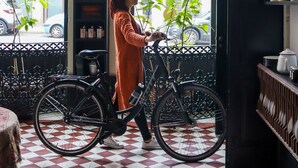 A woman with a bicycle inside a cafe with a checkered floor, large windows, and a visible street view. - Cocorico Luxury House - Porto (Porto)