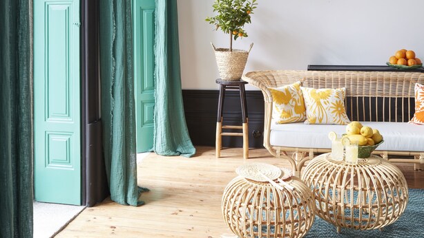 A room with teal curtains, a wicker sofa with yellow cushions, a small table with a plant, and wicker ottomans on a blue rug. - Cocorico Luxury House - Porto (Porto)