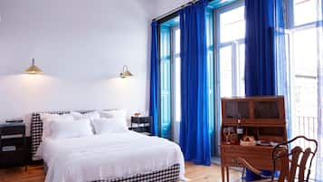 A bedroom with a bed, a nightstand, a dresser, and a window with blue curtains.