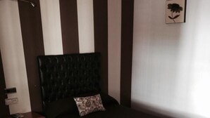 Ein Schlafzimmer mit einem Bett, einem Nachttisch, einer Lampe und einem Wandbild.