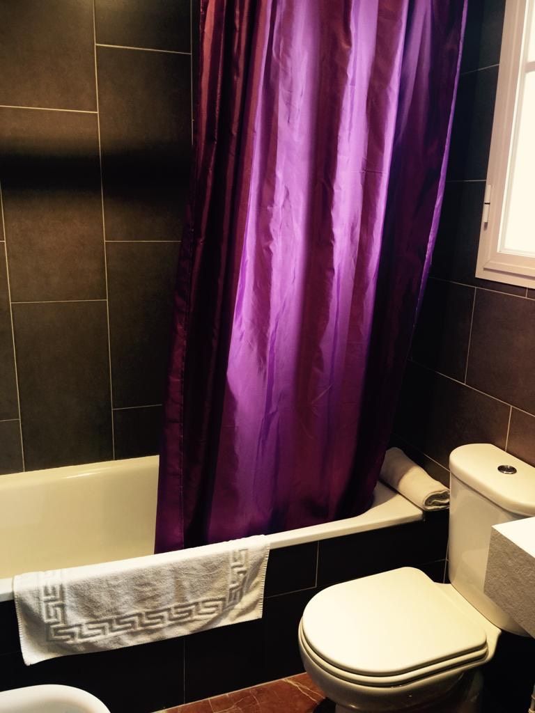 Un baño con bañera, inodoro y cortina de ducha morada.