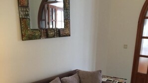 Ein braunes Sofa mit Kissen, ein kleiner Tisch mit Zeitschriften und ein Spiegel an der Wand.