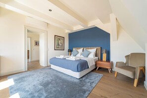 A bedroom with a bed, a chair, a nightstand, and a painting on the wall. - Úttö Luxury Suites (Budapest)