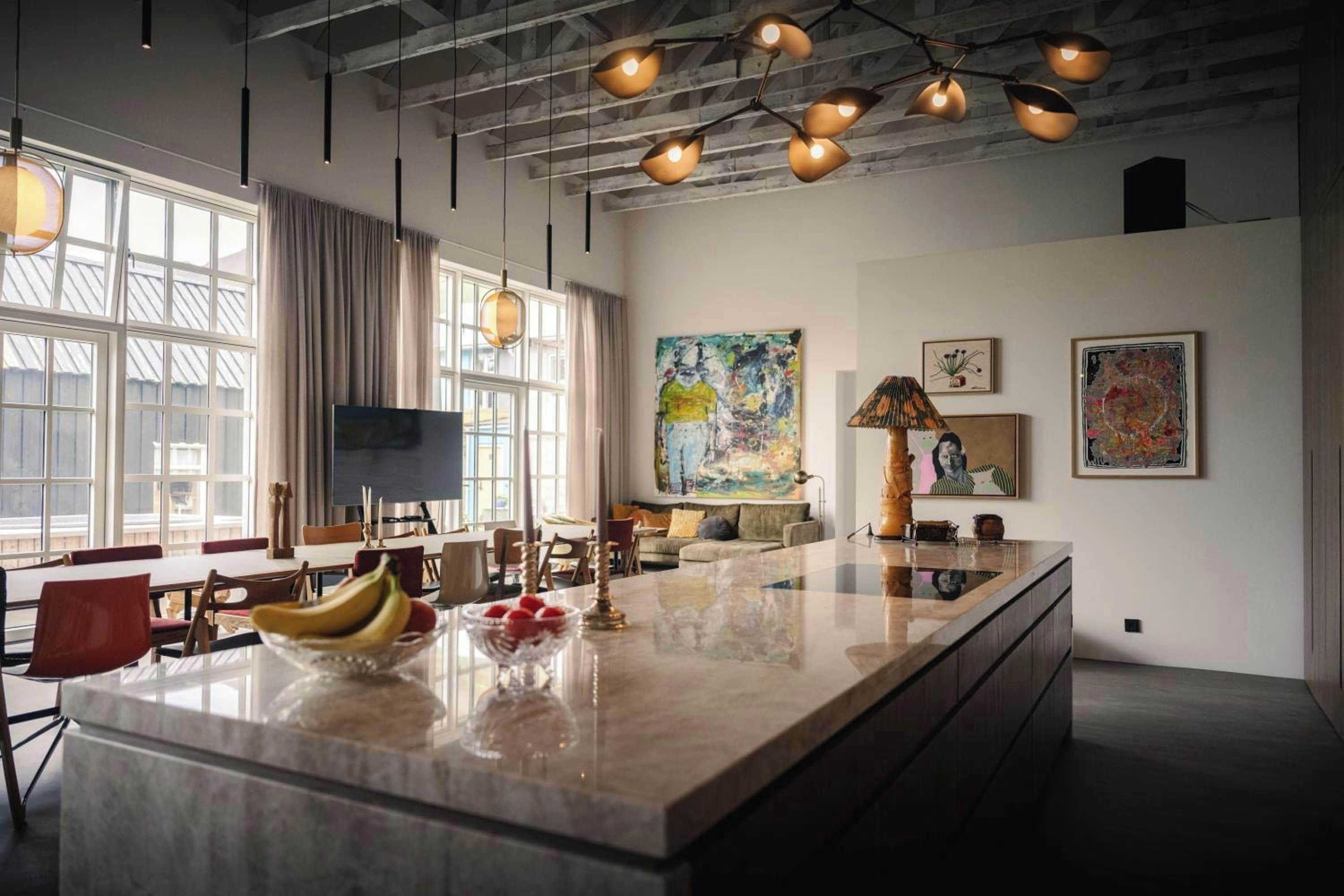 A spacious kitchen with a large island, modern pendant lighting, and artwork on the walls.