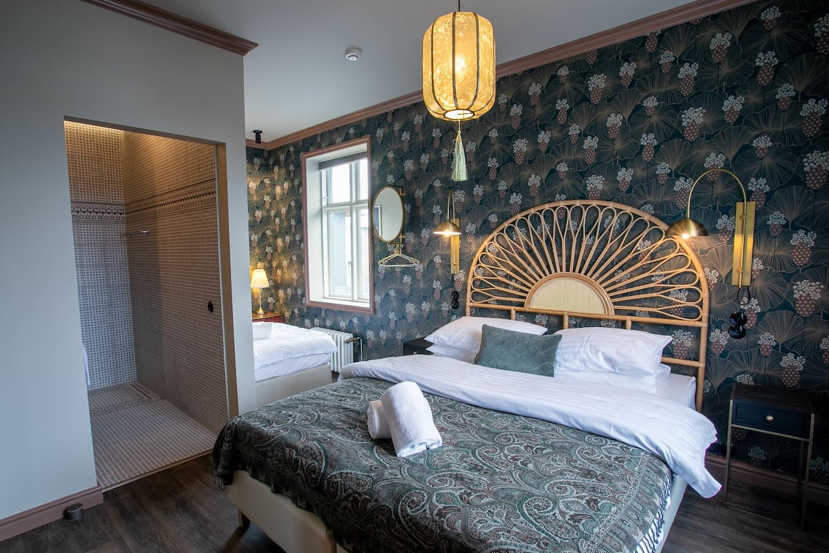 A bedroom with a large bed, a wooden headboard, a window, and a shower area.