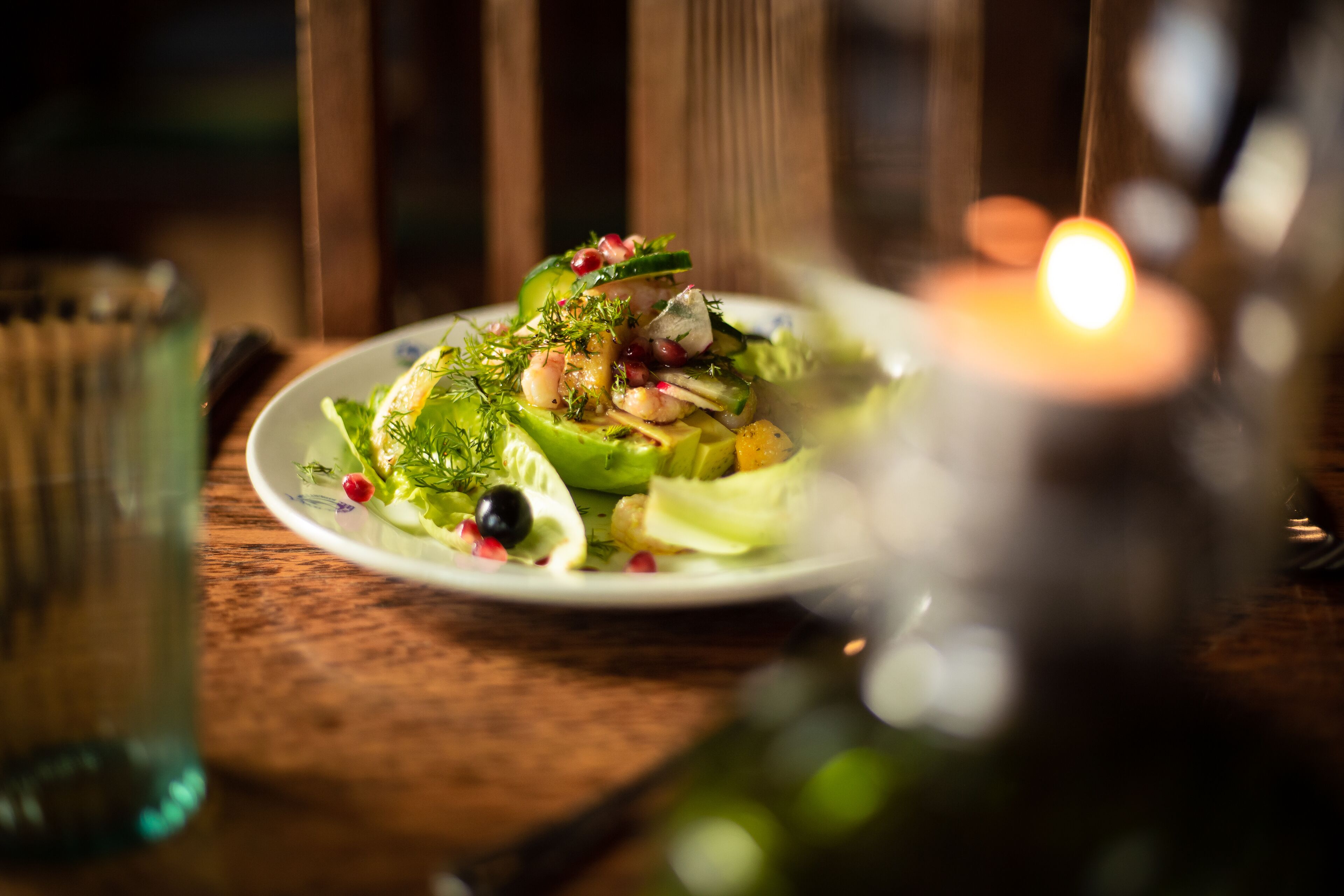 Un plato de comida con diversas verduras y guarniciones sobre una mesa de madera.