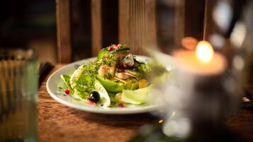 Un plato de comida con diversas verduras y guarniciones sobre una mesa de madera.