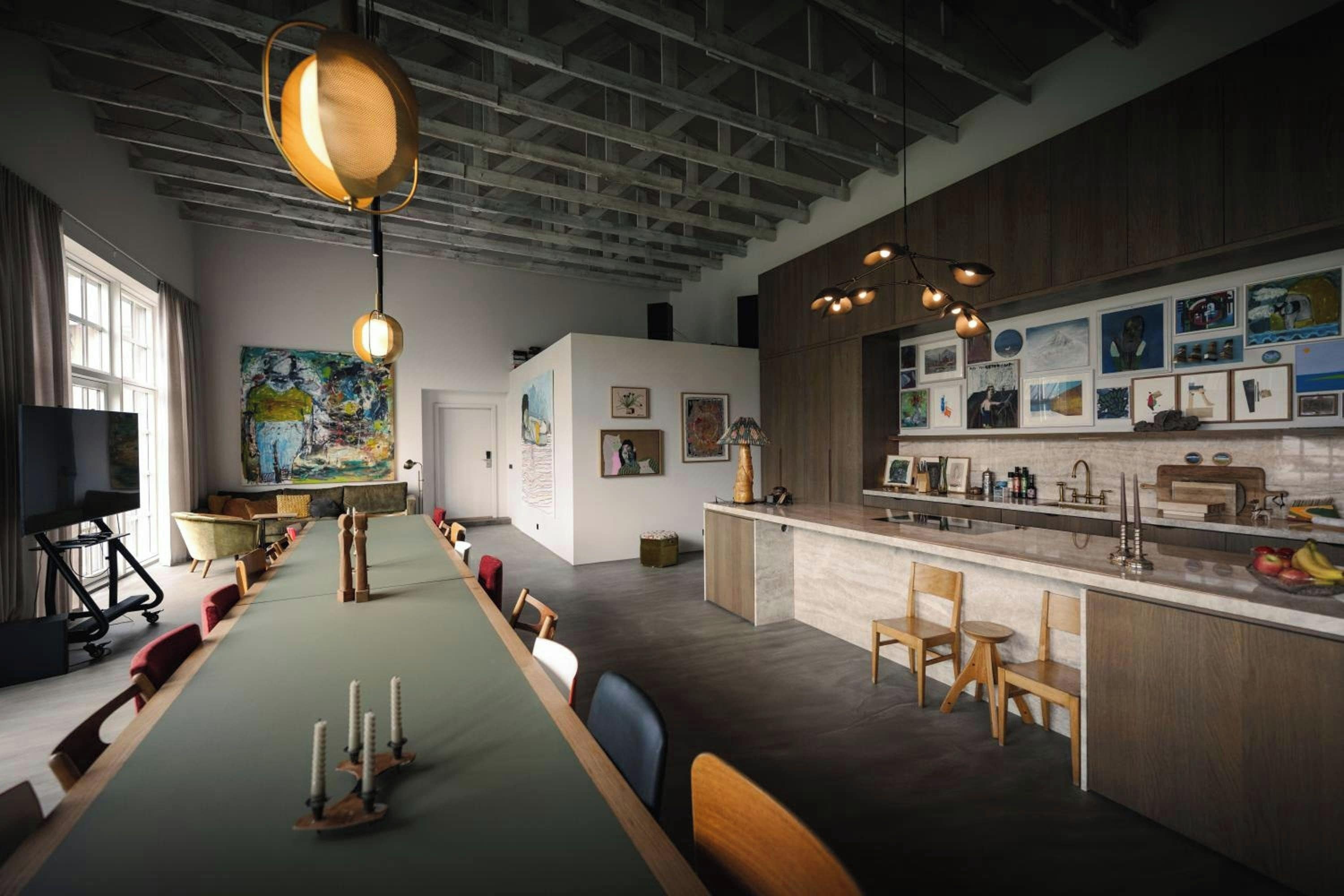 Una cocina moderna con una mesa larga, sillas de madera y una variedad de obras de arte en las paredes.