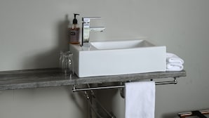 Een badkamer met een witte wastafel, een spiegel, een lijst met een afbeelding en een handdoekhouder.