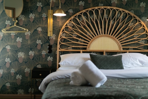 A bed with a rattan headboard, a hanging lamp, and a mirror on the wall.