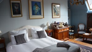 Un dormitorio ordenado con una cama grande, un aparador de madera, una silla y un escritorio.