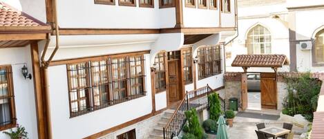 A traditional building with a courtyard, outdoor seating, and a staircase leading to an upper level.