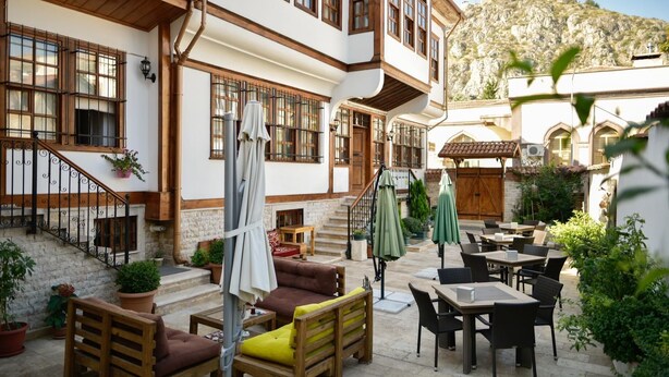 A courtyard with outdoor seating, a staircase, and a mountain backdrop. - Cifte Konak Butik Otel (Amasya)