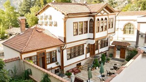 A two-story building with a tiled roof, multiple windows, and a courtyard with outdoor seating. - Cifte Konak Butik Otel (Amasya)
