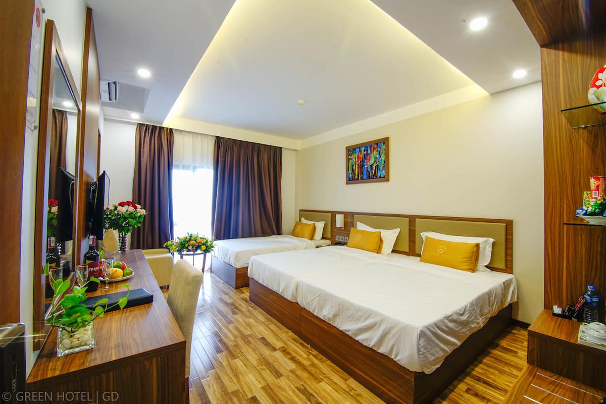 A hotel room with two beds, a wooden desk, a television, and a painting on the wall.