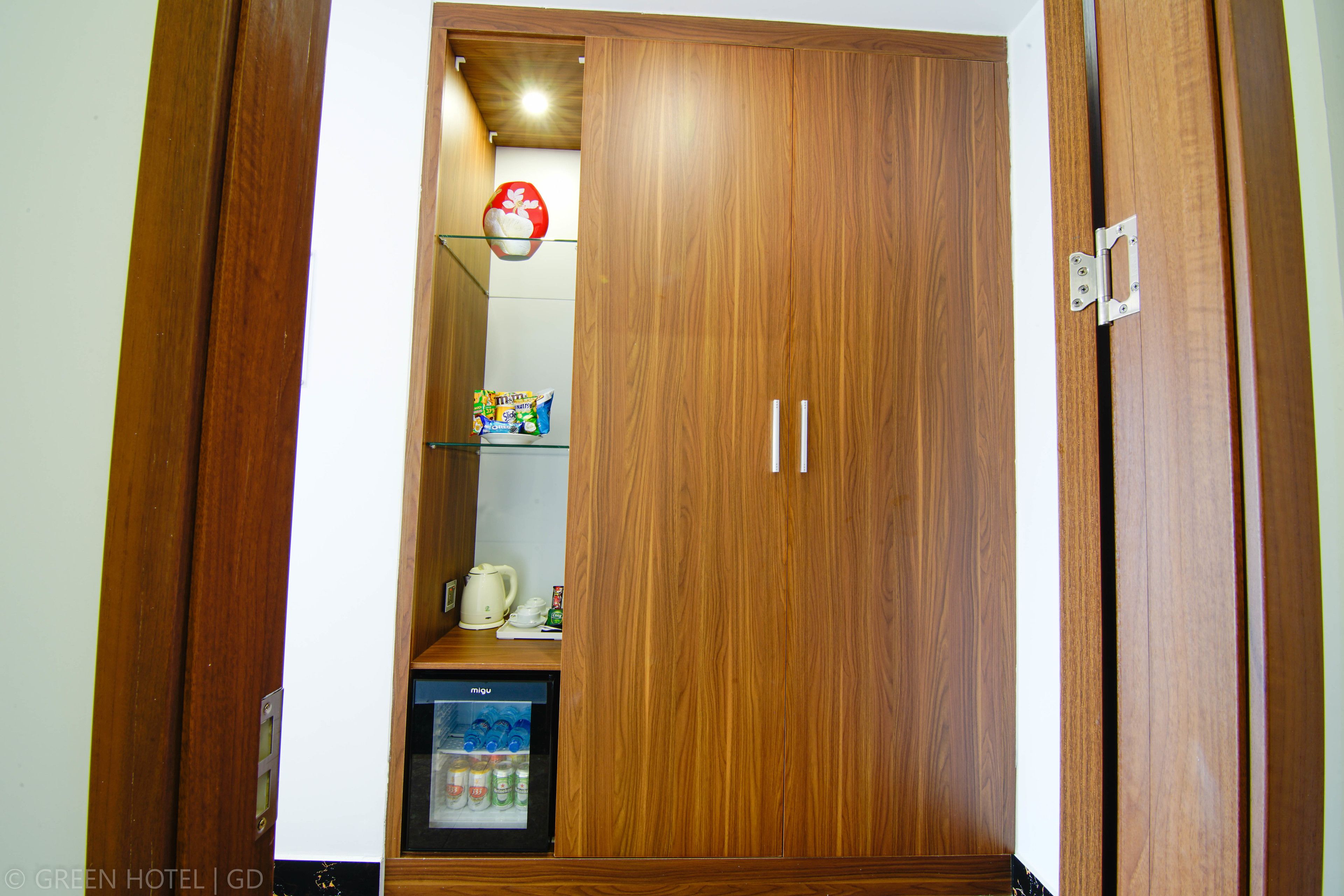 A wooden wardrobe with a built-in mini-fridge and a shelf with snacks.