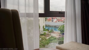 A room with a view of a building with a blue roof and a pool. - Green Hadong Hotel (Hanoi)