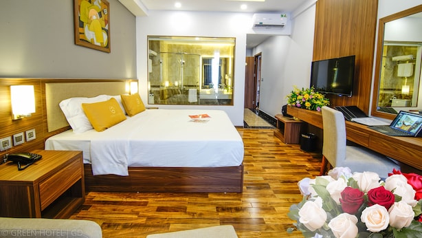 A hotel room with a bed, bedside tables, a desk with a laptop, a TV, and a large mirror. - Green Hadong Hotel (Hanoi)