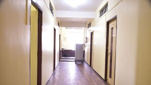A long, narrow hallway with doors on both sides, leading to a bright room at the end. - Hotel Drishti Inn (Nagpur)