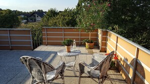 A patio with wicker chairs, a round table, and potted plants. - BellaCaro (Loehne)