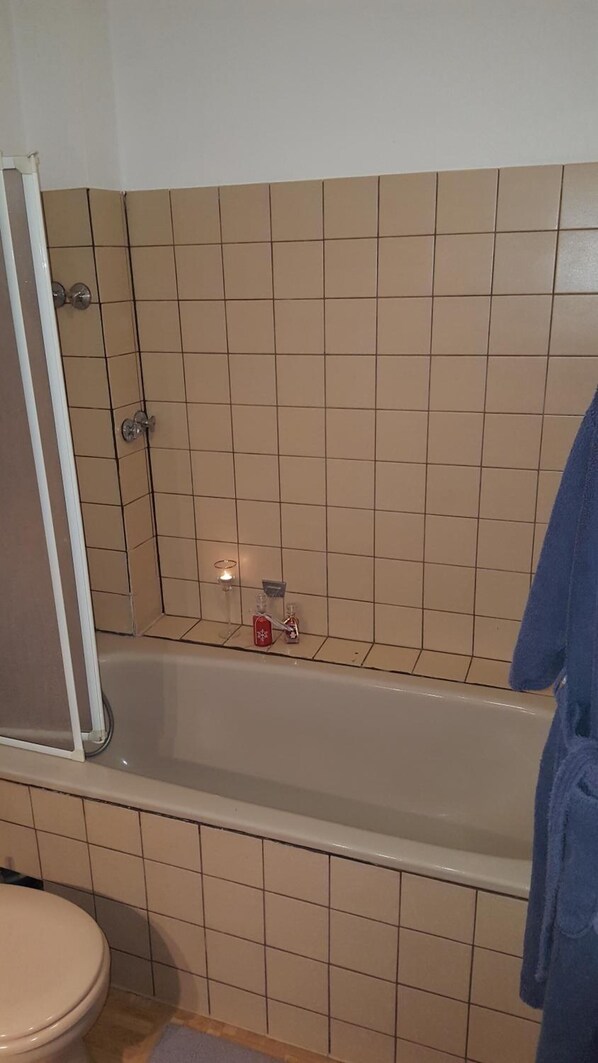 A bathroom with a bathtub, toilet, and shower area.