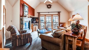 A cozy living room with a fireplace, a television, and a dining area with a table and chairs. - Jackpine 8021 (Keystone)