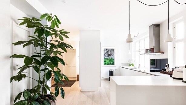A modern kitchen with a large island, white cabinetry, and pendant lighting. - Dinesen Collection Condo by Royal Theatre (Copenhagen)