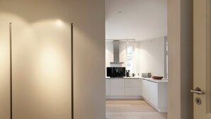 A modern kitchen with white cabinetry, a built-in oven, and a window providing natural light. - Dinesen Collection Condo by Royal Theatre (Copenhagen)