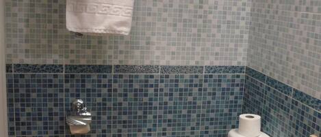 A bathroom with a toilet, sink, and a towel hanging on a rack.