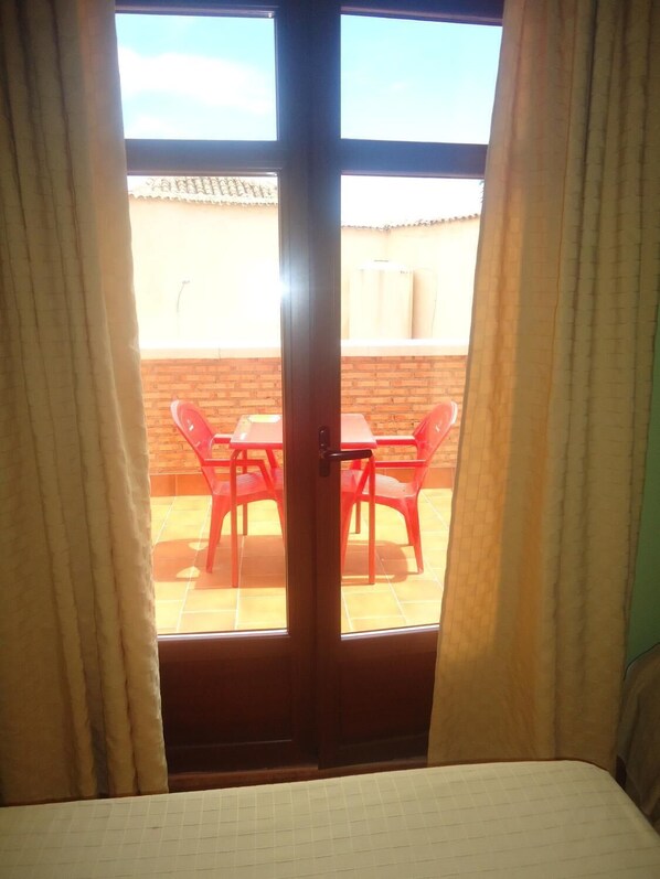 A room with a sliding glass door leading to an outdoor patio with a table and chairs. - Hostal Posada Entreviñas (Valdepenas)
