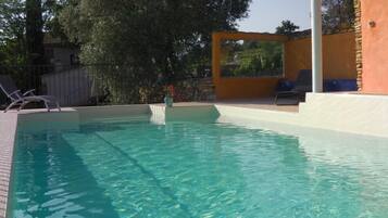 Een buitenzwembad en ligstoelen