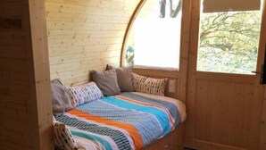 Una habitación acogedora con detalles de madera, un ventanal curvo y una cama con ropa de cama a rayas.