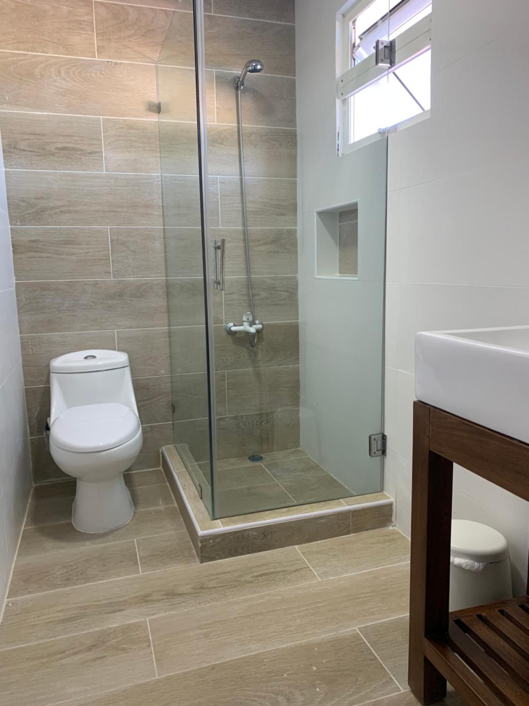 A modern bathroom with a glass-enclosed shower, a toilet, and a vanity with a mirror.
