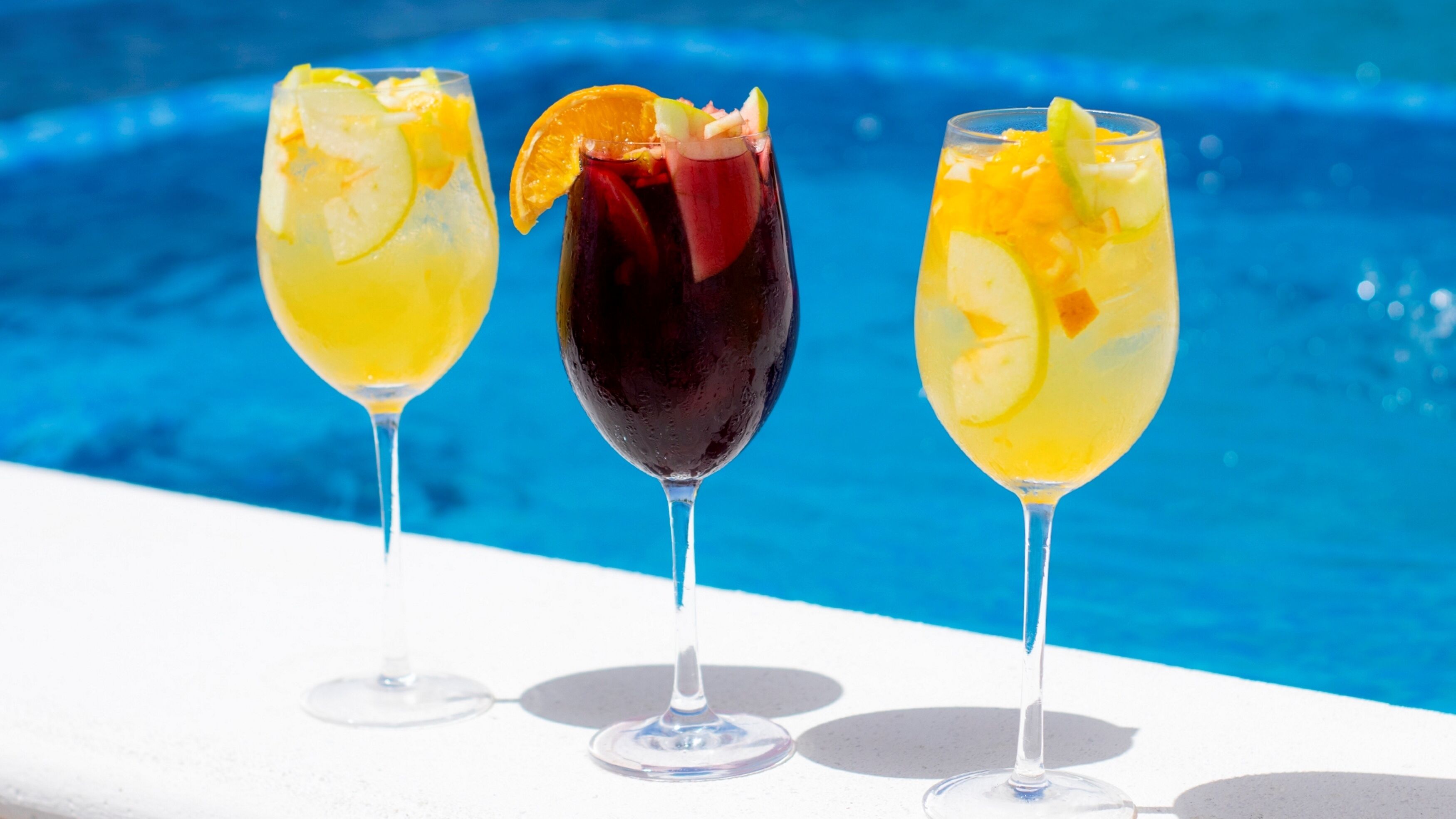 Tre cocktails ved en pool.